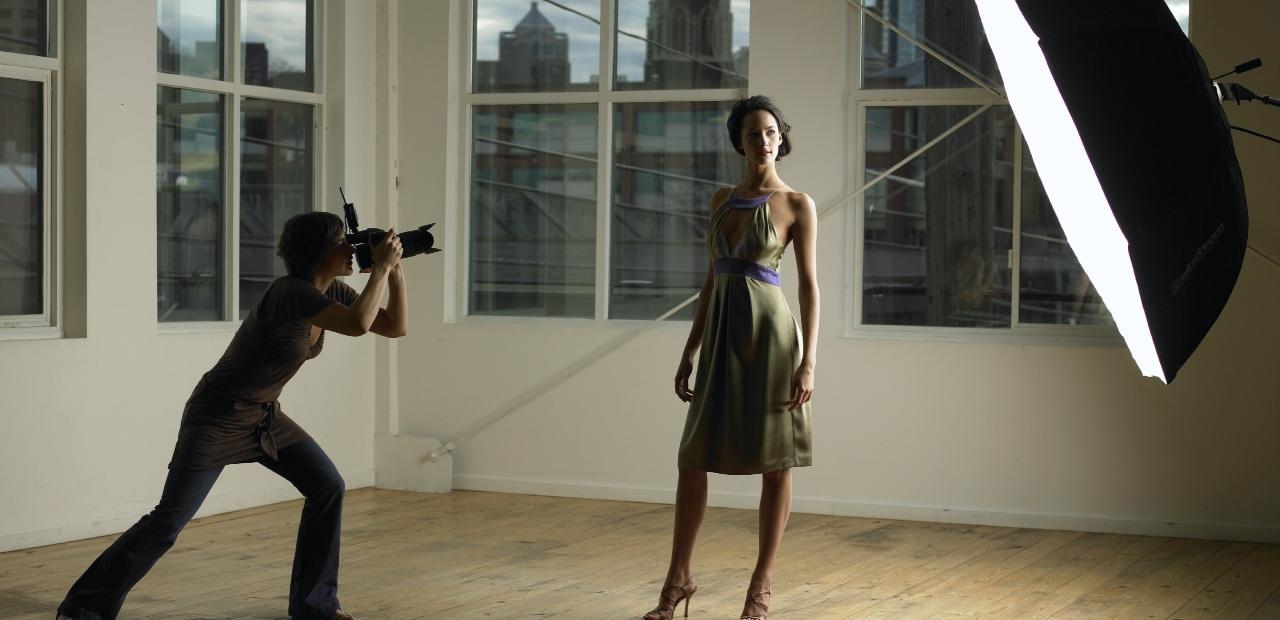 Woman photographing young female model in photo studio, dusk - stock photo