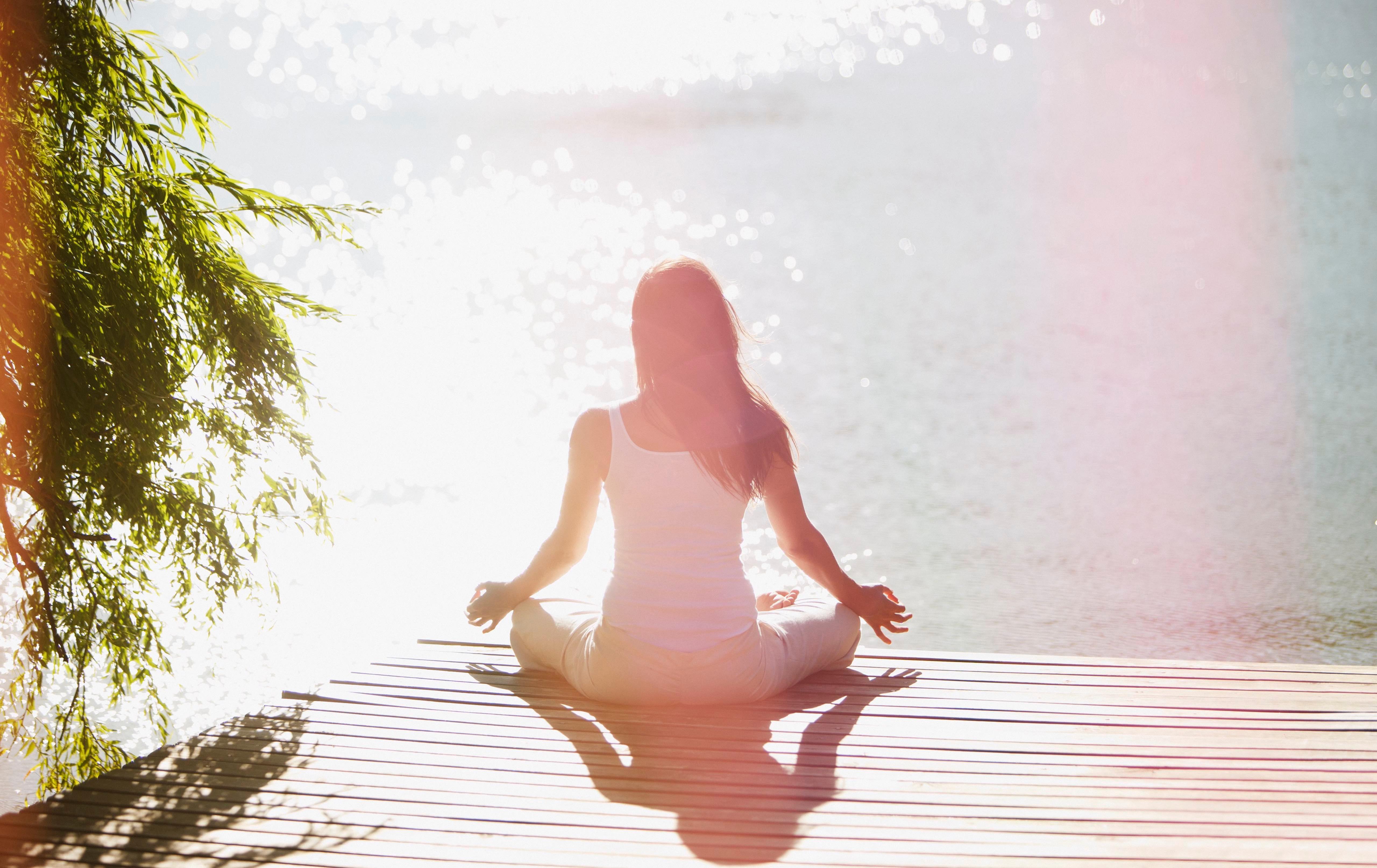 Woman meditating on a dock.