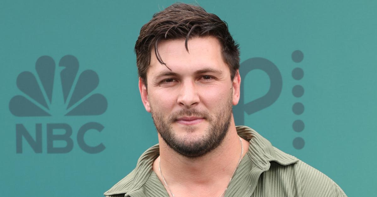 Brock Davies wears an olive green short-sleeve button up while posing on the red carpet at the 2024 People's Choice Awards.