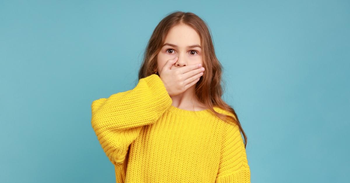 little girl with hand over mouth