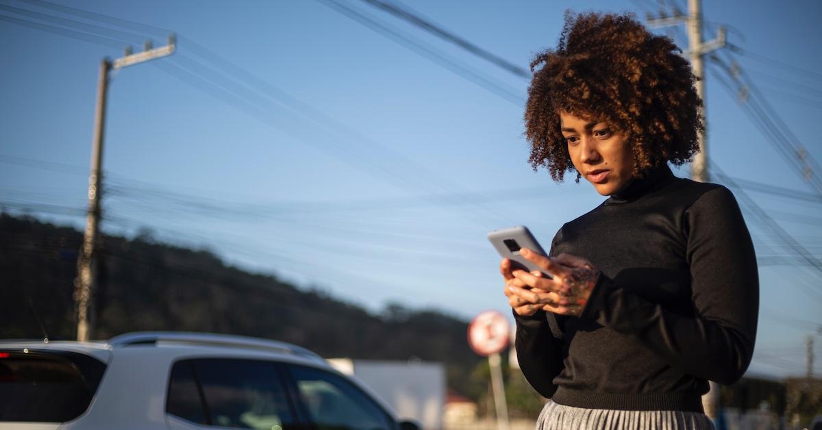 A woman on the phone standing away from her car