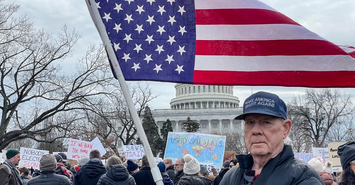 A man holding an upside down American flag out of protest