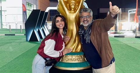 Sara Al Madani and her father Abdul Wahab Al Madani pose on either side of a Fifa World Cup statue