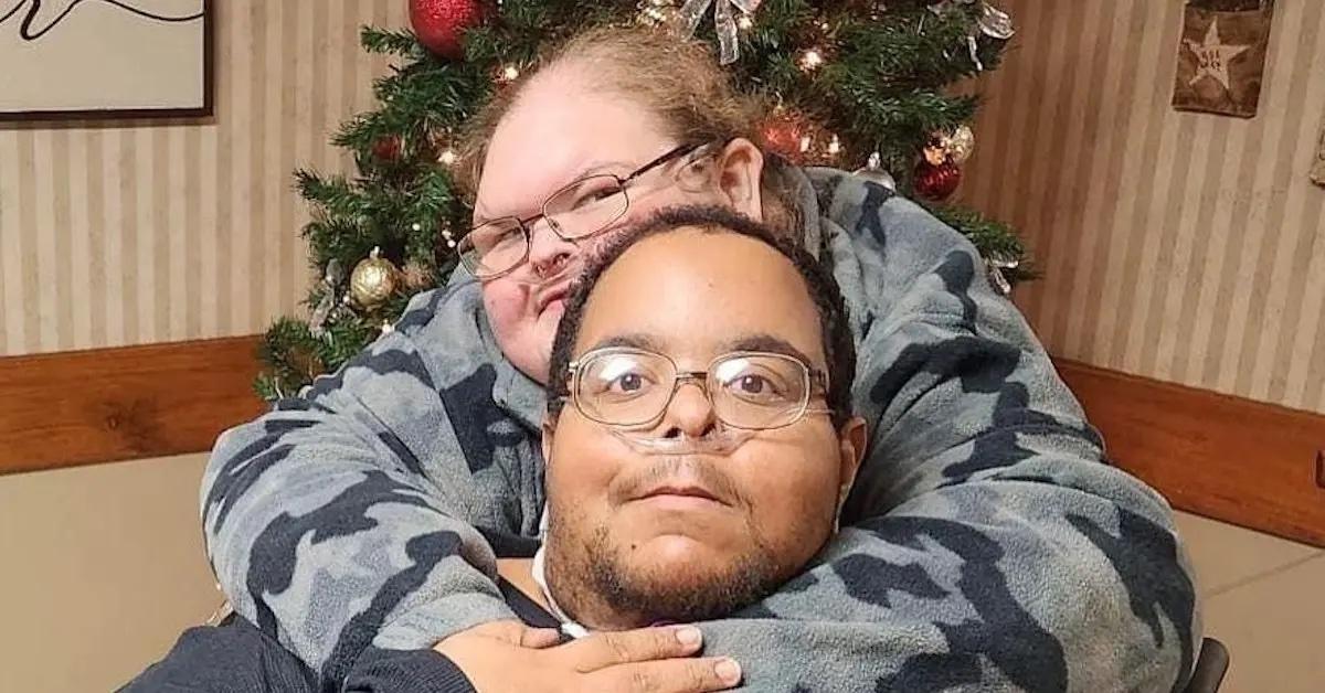 Tammy and Caleb sitting in front of a Christmas tree