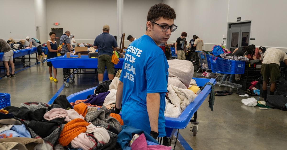 A worker rolling clothing items away