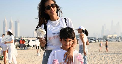 Sara Al Madani stands on the beach with her arm over her sons shoulder at a beach cleanup event
