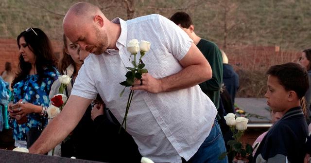 A former Columbine student places flowers at the memorial in Colorado