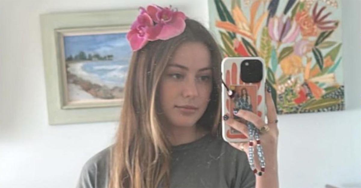 Caroline Calloway takes a mirror selfie with a pink flower in her hair.