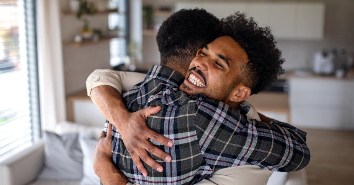 Young happy adult brothers hugging.