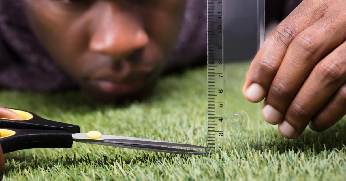 man cutting the measured grass with scissor picture id