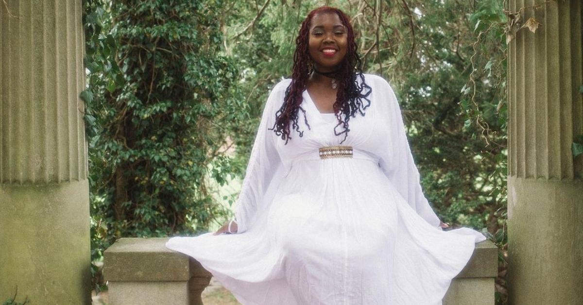 Ashley from 90 Day Fiance in a white dress outside on a stone bench