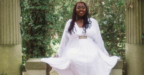 Ashley from 90 Day Fiance in a white dress outside on a stone bench