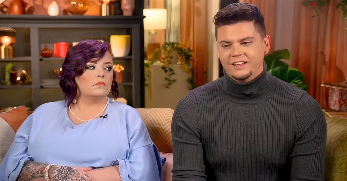 Catelynn Lowell Baltierra, sporting short purple hair and a light blue blouse, sits beside Tyler Baltierra, donning a gray turtleneck, on the couch during a 'Teen Mom' confessional.