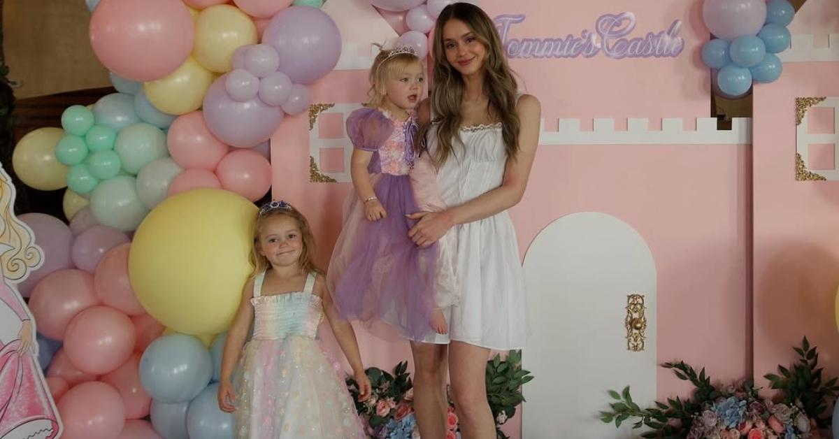 Mikayla Matthews with her two daughters in front of a balloon arch