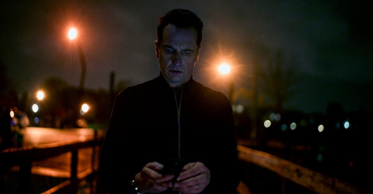 Nile looks at his phone on a dark street