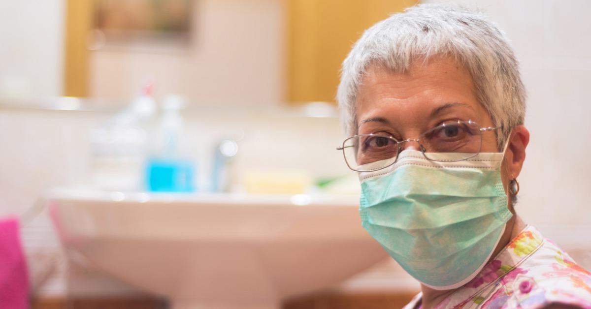 senior woman wearing face mask doing housework picture id