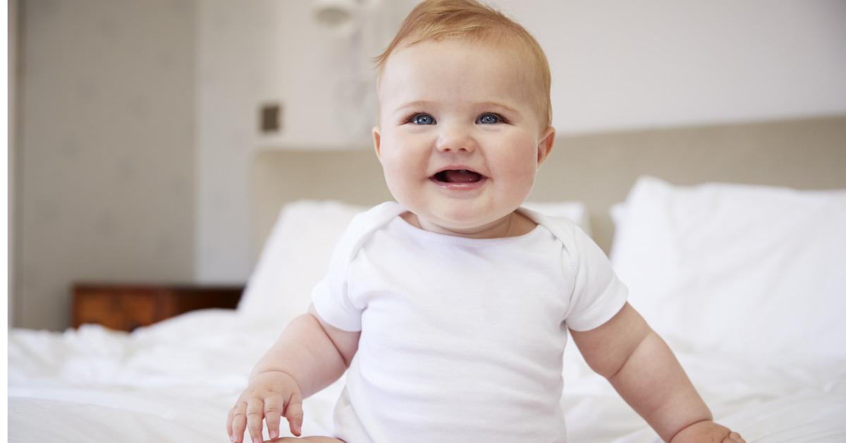 happy baby boy sitting on parents bed picture id