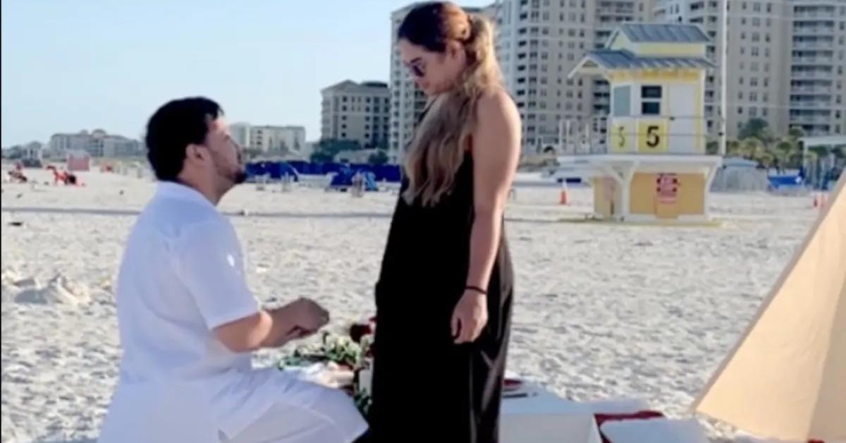 A couple goes viral after their beach proposal is ruined by a woman.