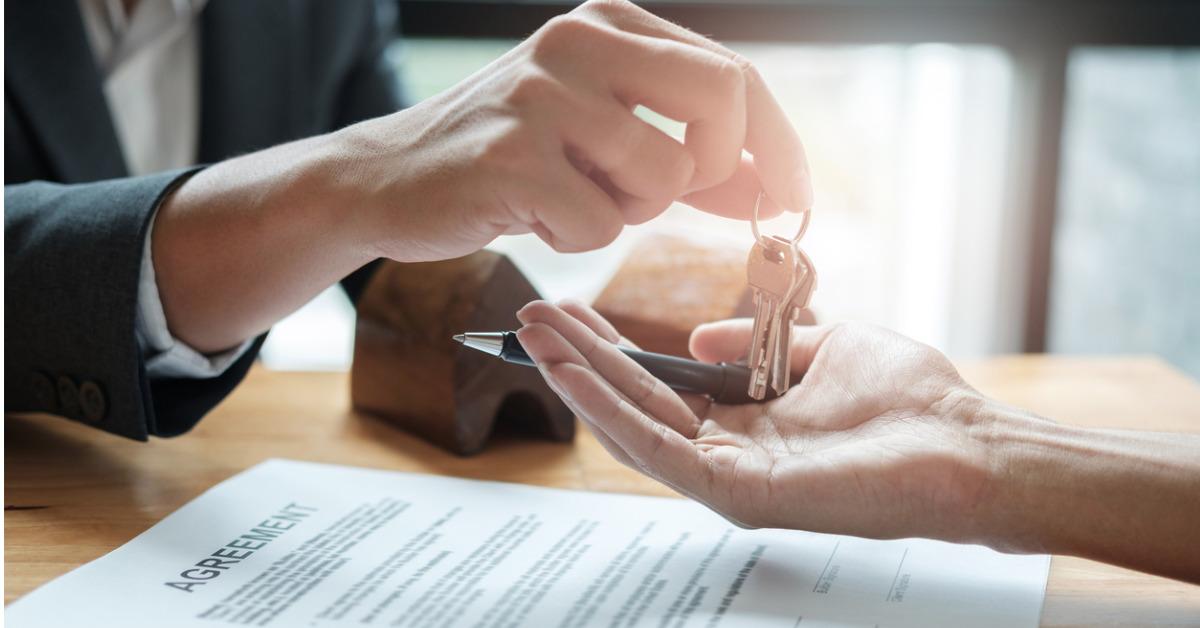 estate agent giving house keys to man and sign agreement in office picture id