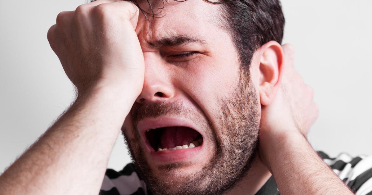 man wearing a black and white shirt cries out in pain picture id