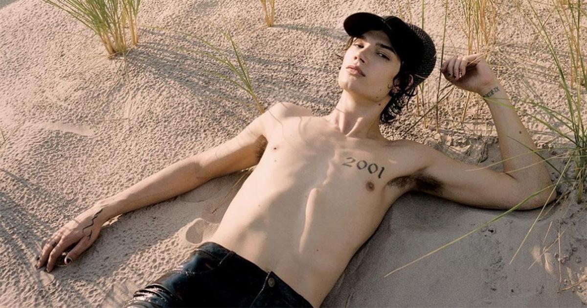 Ian Charles laying on the beach without a shirt on. 