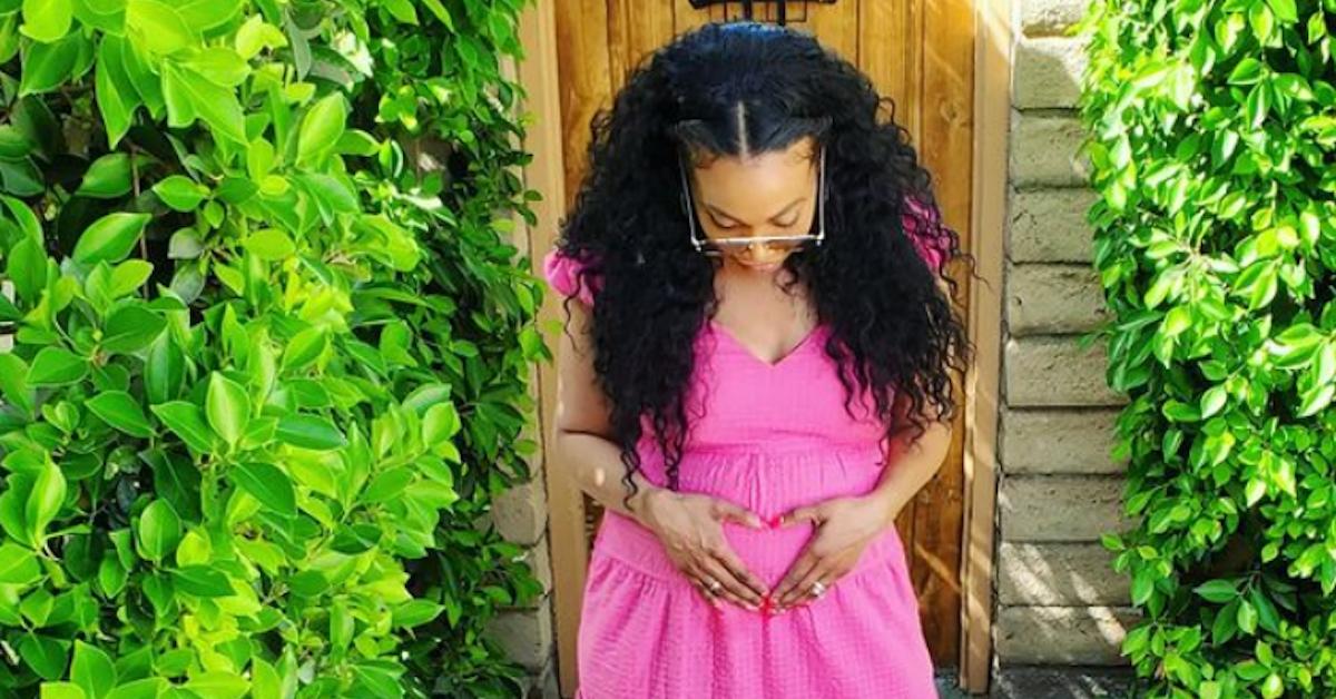 Shea Hicks Whitfield makes a heart shape with her hands on her belly