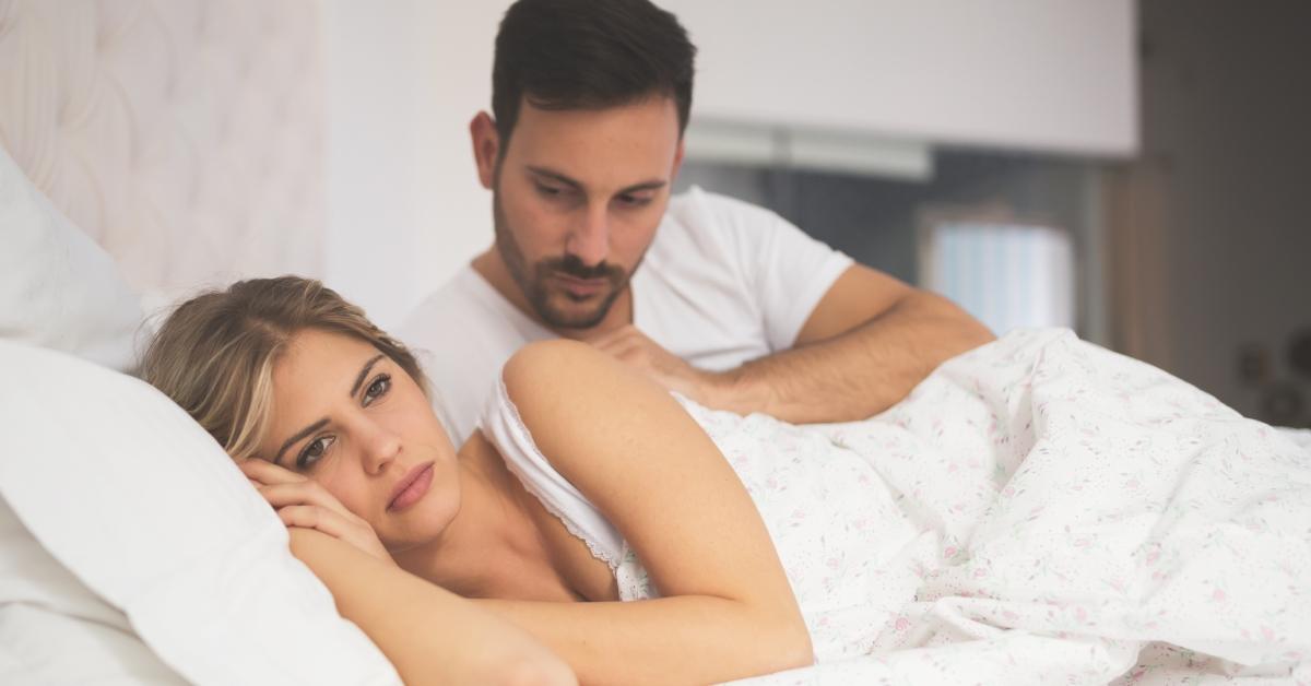 A man tries to comfort visibly upset woman in bed