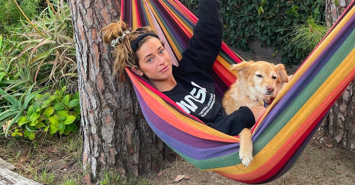 Jo Wenberg relaxing in a rainbow hammock with her dog.