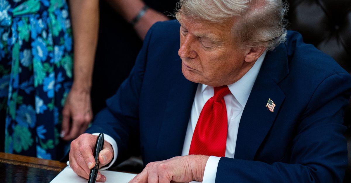 Donald Trump signing an order in the Oval Office.