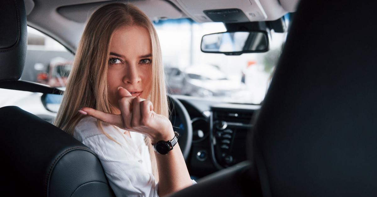 A woman pointing her finger and turning to the backseat of her car.