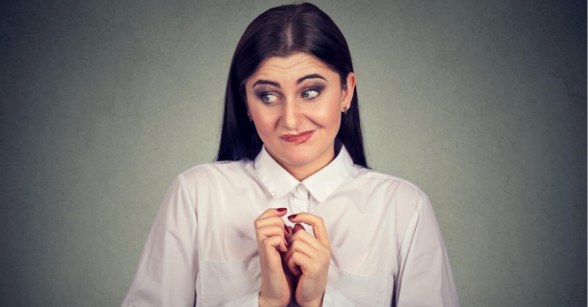 portrait young woman in awkward situation playing nervously with picture id