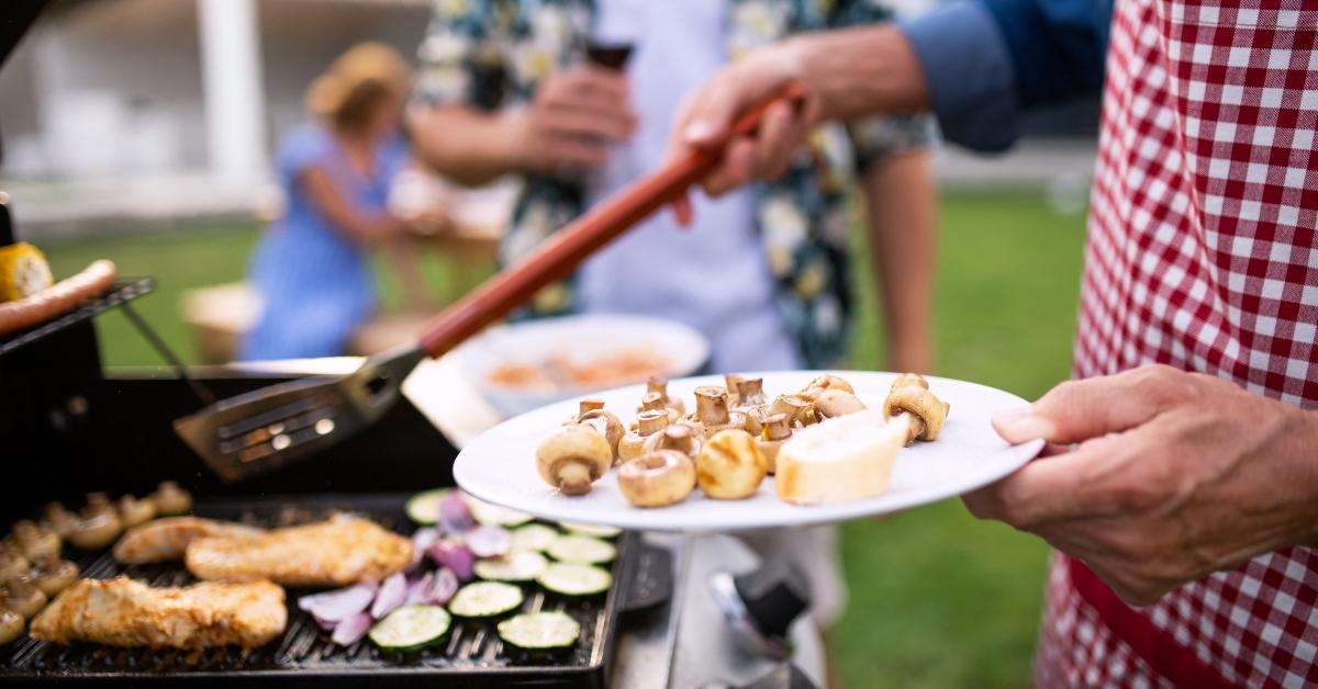 Midsection of family outdoors on garden barbecue, grilling. - stock photo