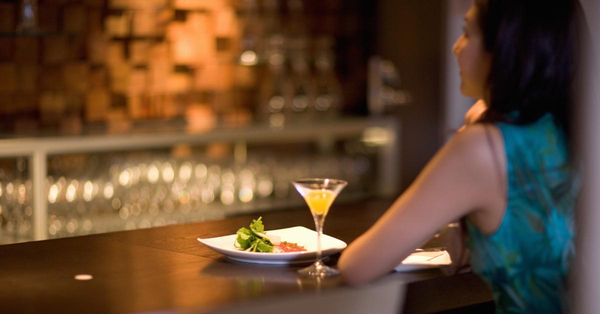 A young woman sitting alone at a bar