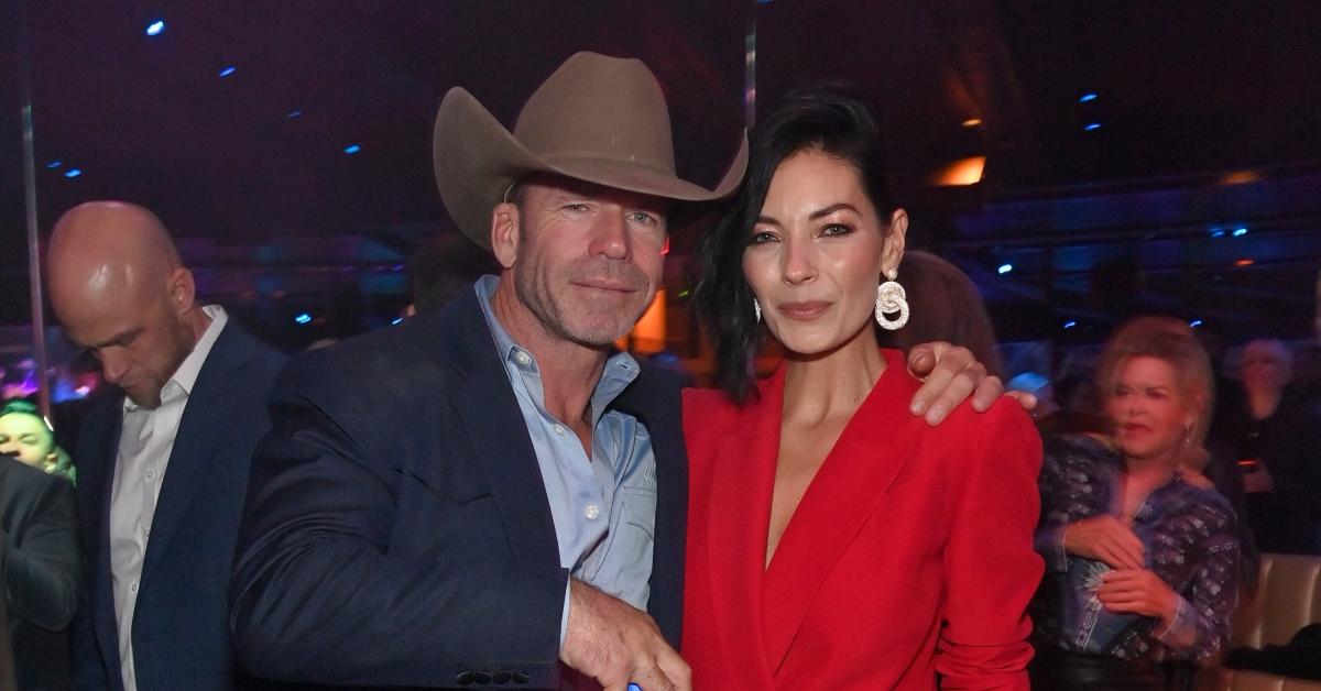 Taylor Sheridan in a cowboy hat and wife Nicole in a red dress.