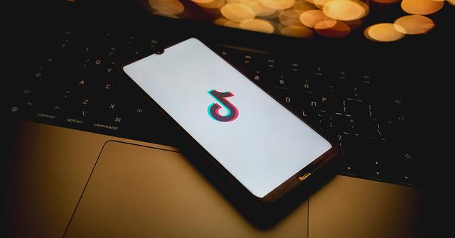 A TikTok logo on a phone screen on a laptop.