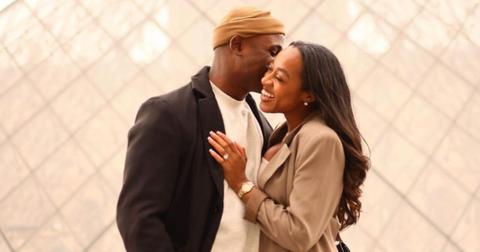 Silas Cooper kissing wife Jasmine Ellis Cooper in front of a photo backdrop
