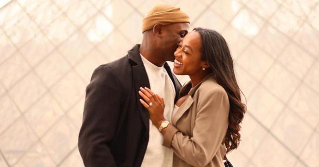 Silas Cooper kissing wife Jasmine Ellis Cooper in front of a photo backdrop