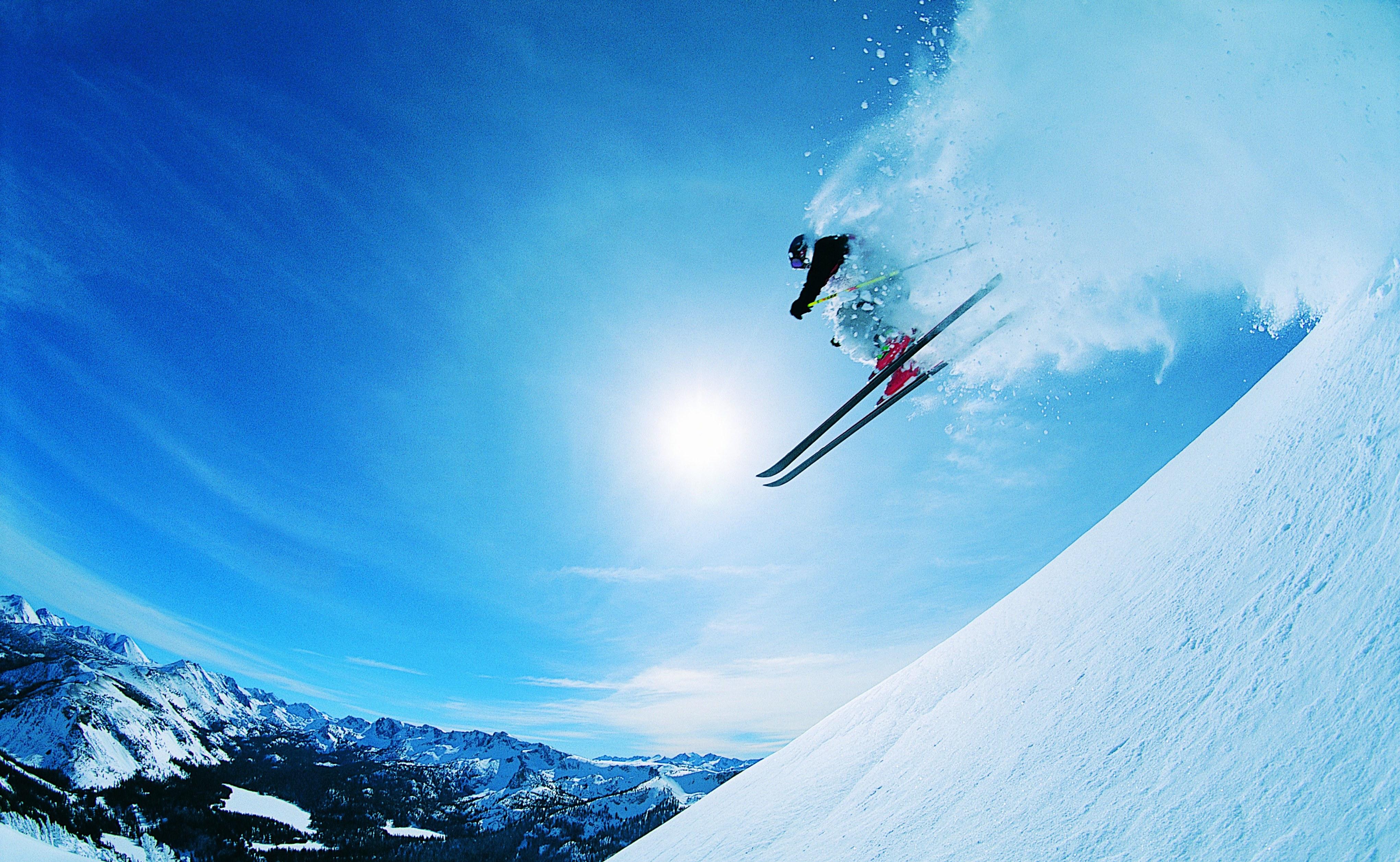 A man enjoys the snow by skiing down a high slope.