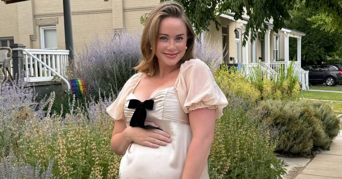 Whitney poses for a photo outside holding her pregnant belly