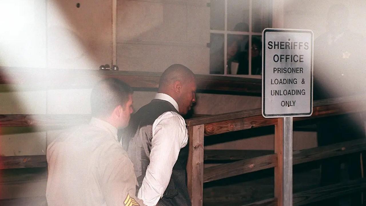 Mike Tyson walking into the sentencing hearing, escorted by police officer.