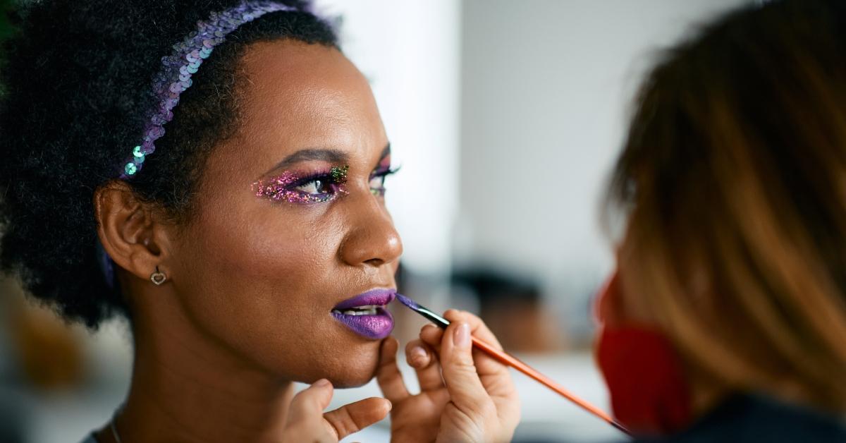 A makeup artist putting makeup on a woman for a Mardi Gras celebration