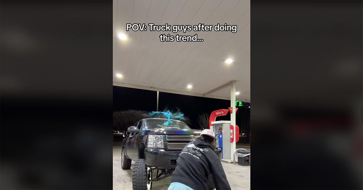 A young man throwing a blue slushie at his truck. 