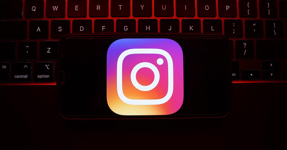 The Instagram logo on a phone with a keyboard behind it. 