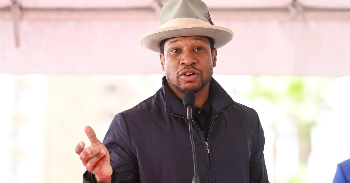 Jonathan Majors wearing a hat, giving a speech at Michael B. Jordan's Hollywood Walk of Fame star ceremony in March 2023