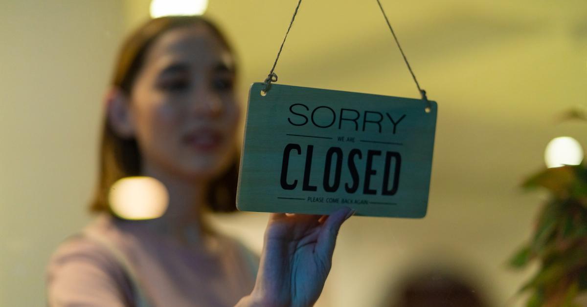 Restaurant server flips over the "closed" sign on the door.