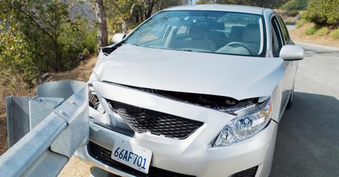 A car wrecked on road guardrail - stock photo