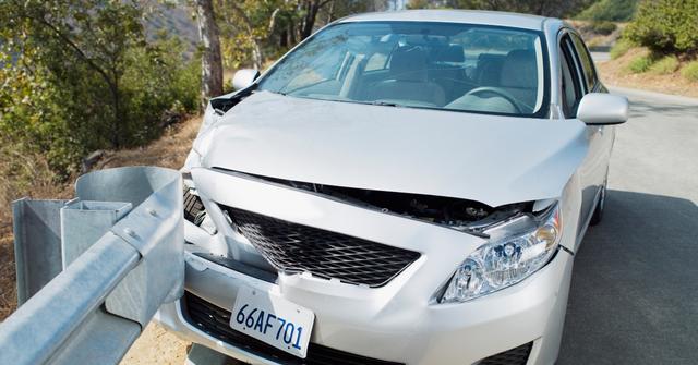 A car wrecked on road guardrail - stock photo