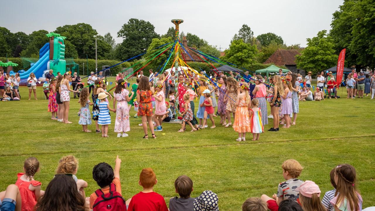 Children dancing around a maypole on May Day in England