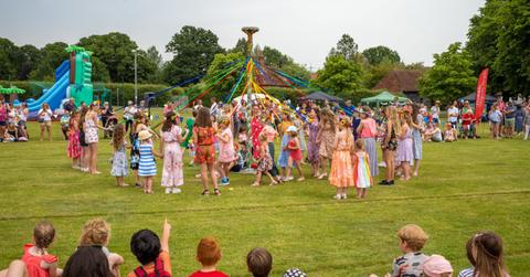Children dancing around a maypole on May Day in England