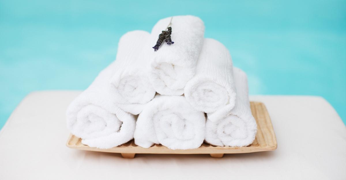 Rolled towels with lavender on tray at poolside - stock photo